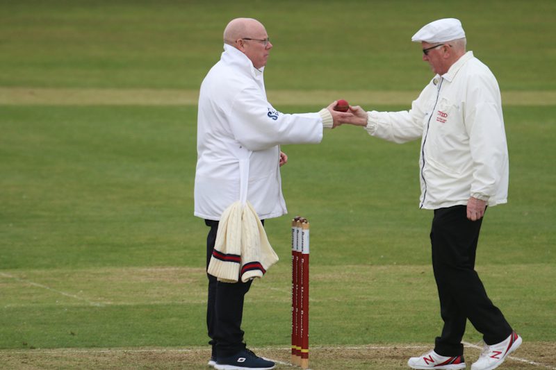 Cricket umpires exchange the cricket ball