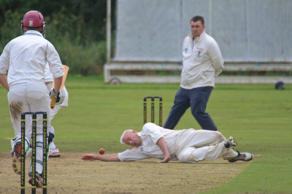 cricketer stops the ball by diving on the ground