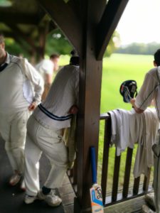 cricket club pavilion, players rest on the wooden rail outside