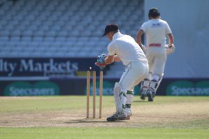 picture of a wicketkeeper removing the bails (picture taken from behind the player)