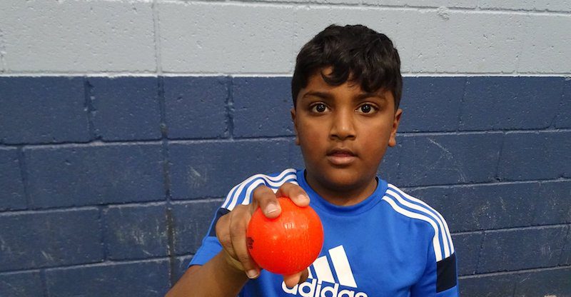 boy shows cricket ball grip with orange wind ball
