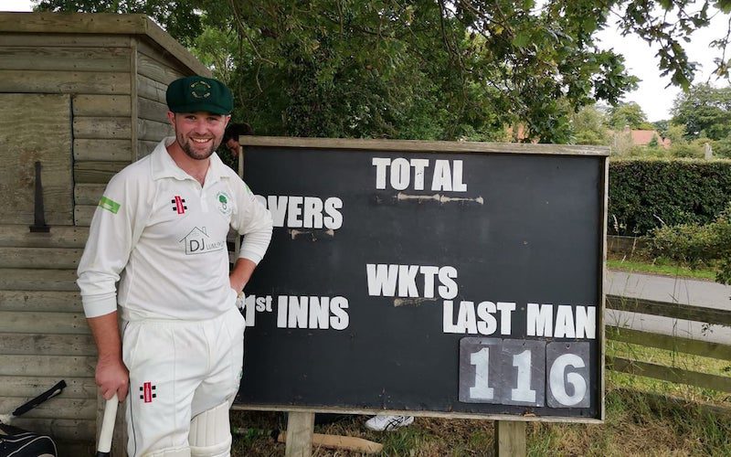 Great Habton Cricket Club player poses in front a scoreboard